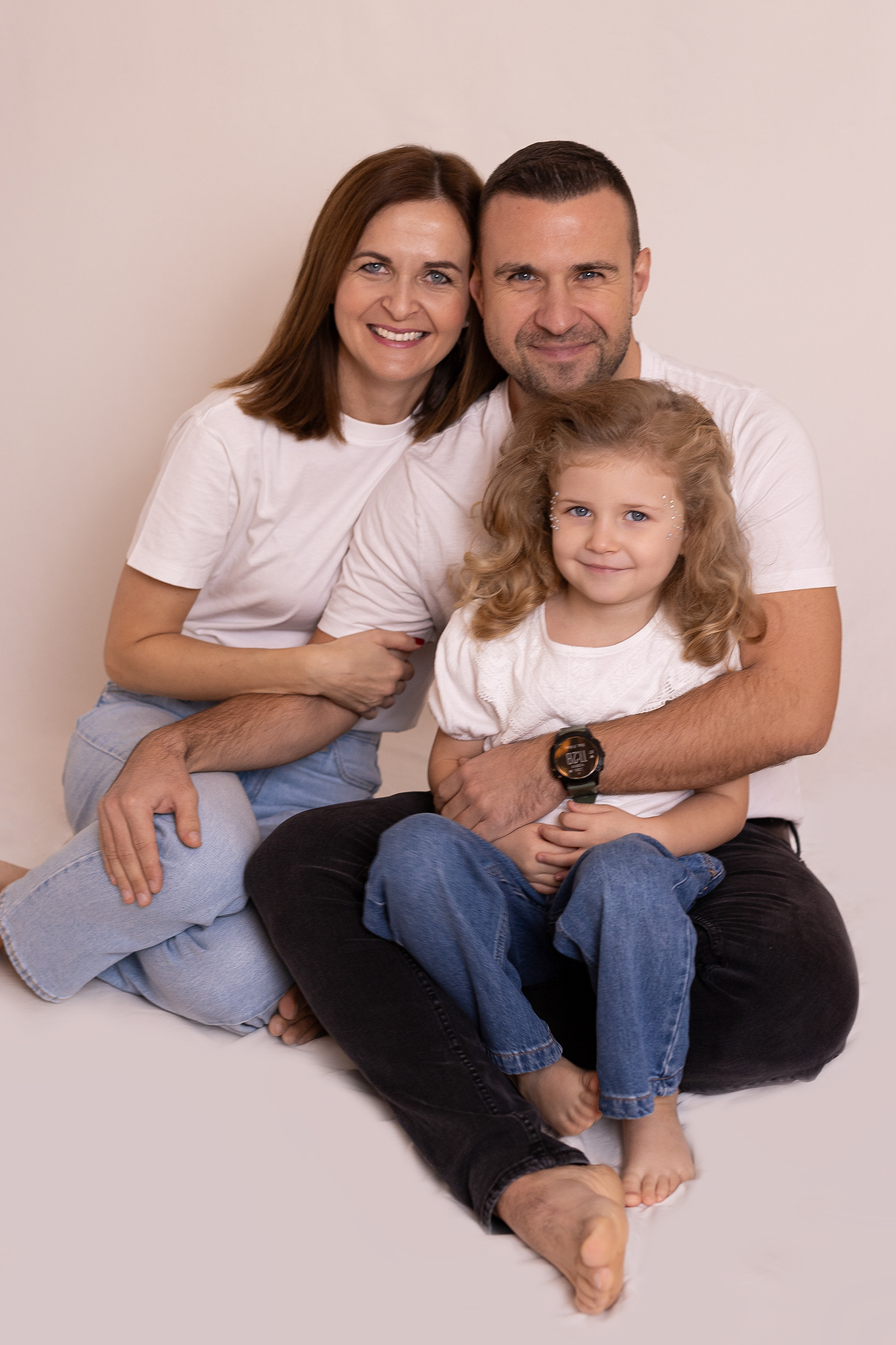 Kisgyermekes család ül összebújva a családi fotózáson miskolci stúdióban, minimál stílusban.