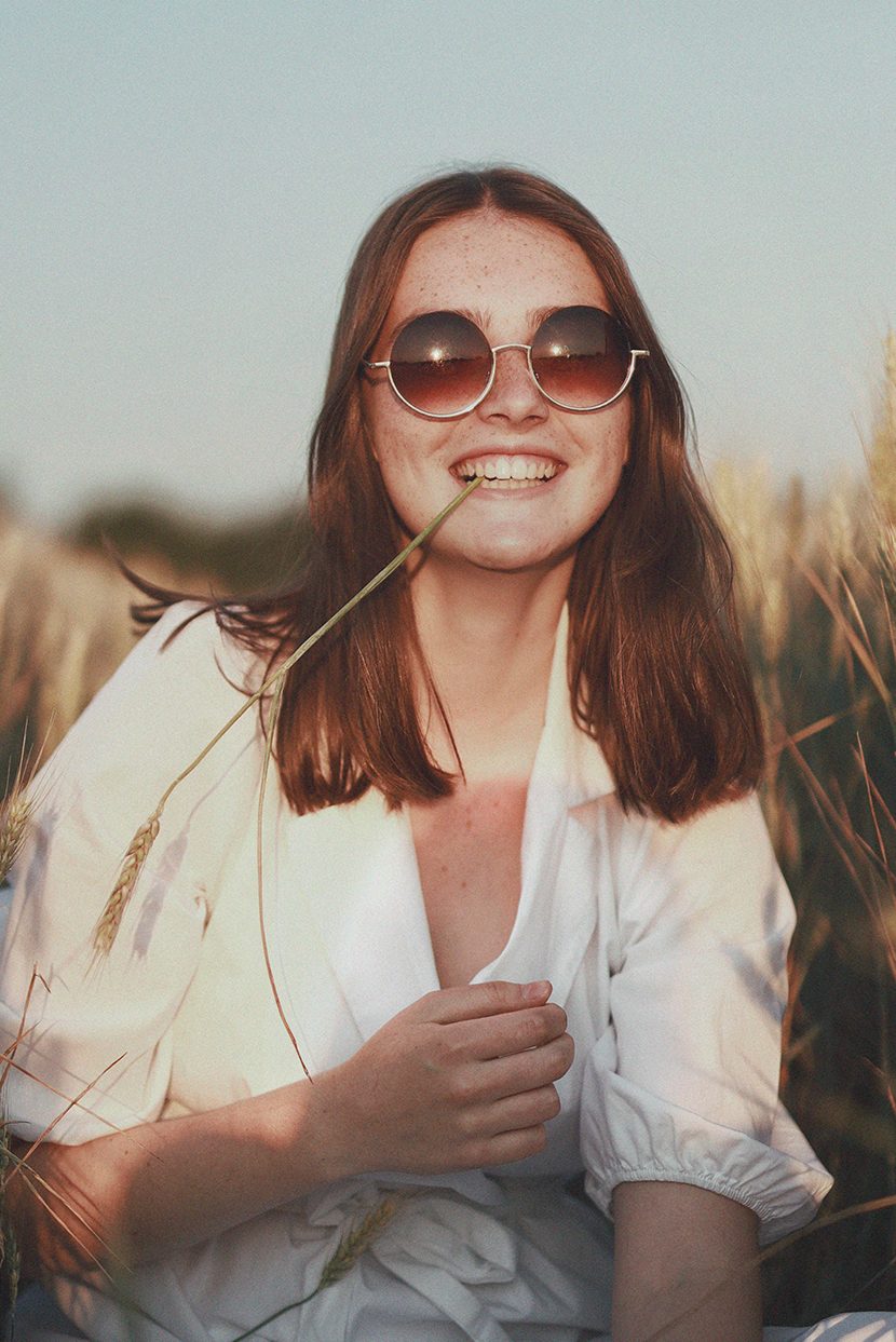 szép nő ül a mező közepén boldogan nevetve