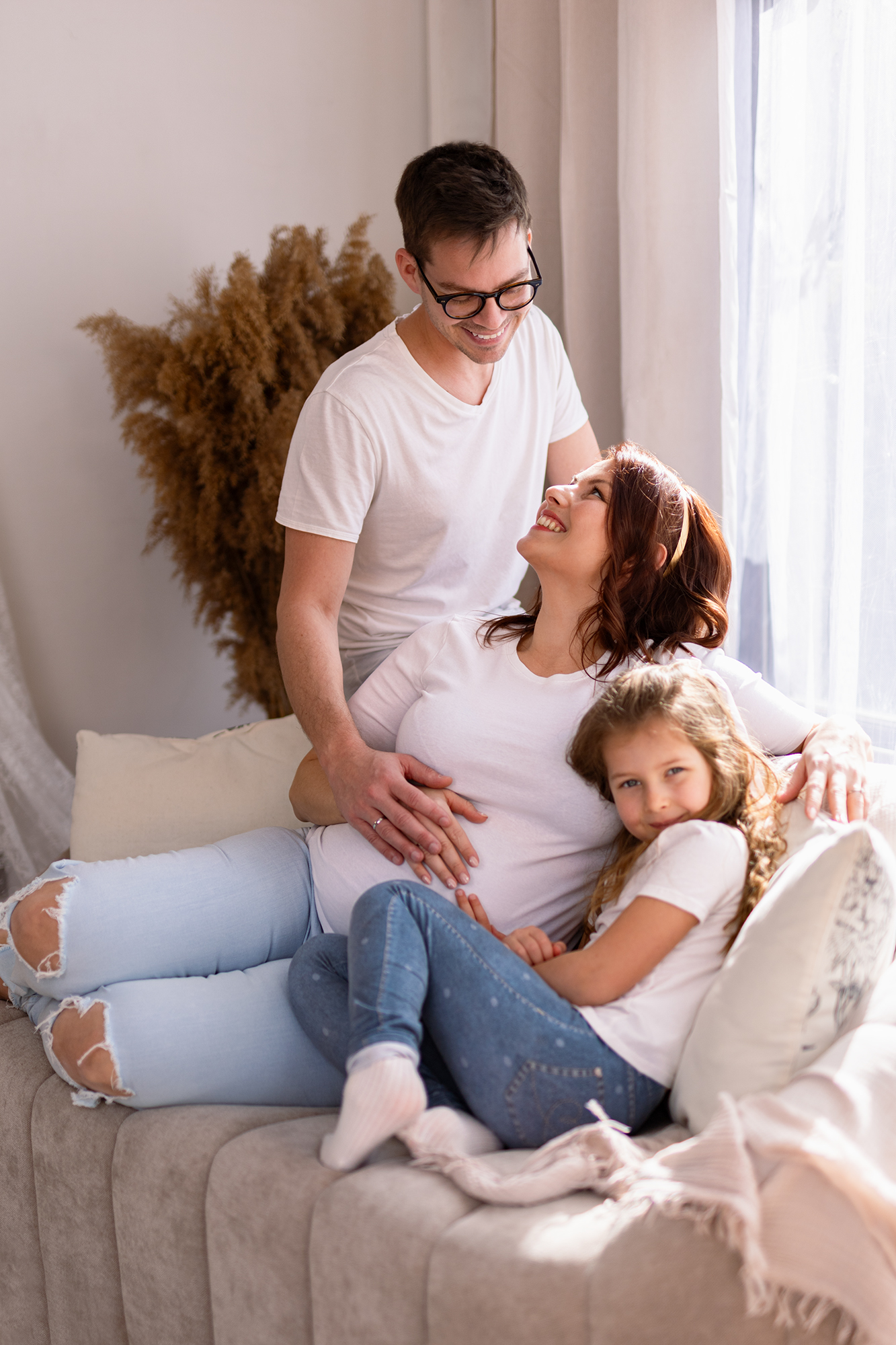 világos hangulatú lifestyle stúdiós kismamafotózás családdal.