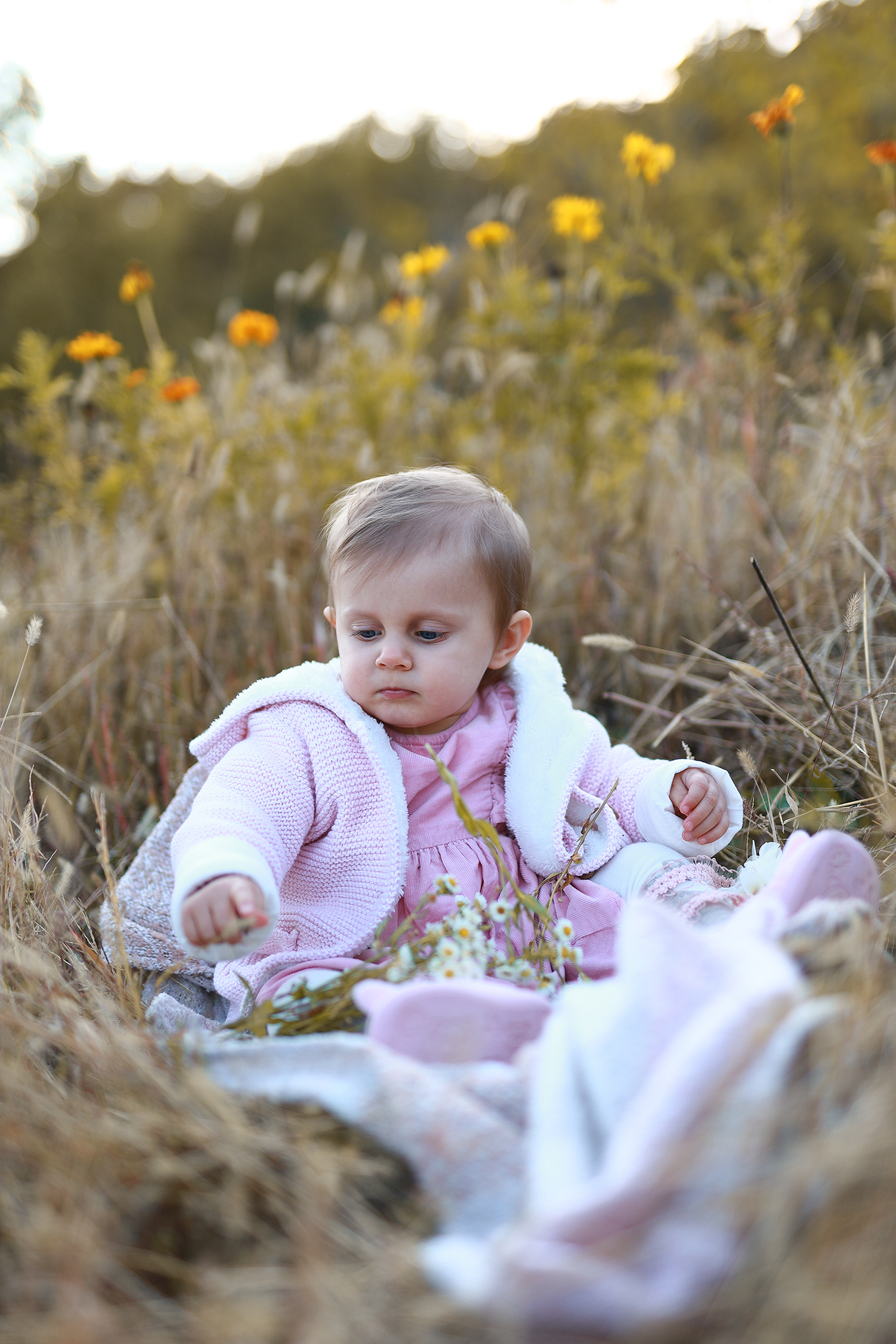 baba a nagy fűben ücsörög rózsaszín ruhában.