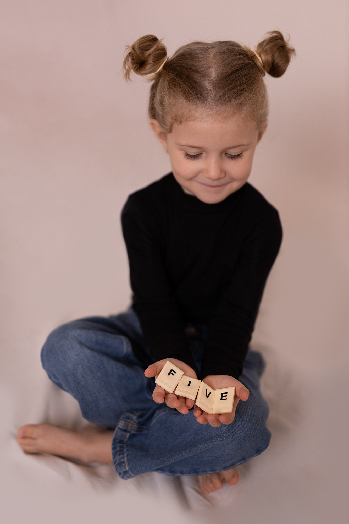 kislány mutatja egy játék betűivel, hogy 5 éves, szülinap fotózáson