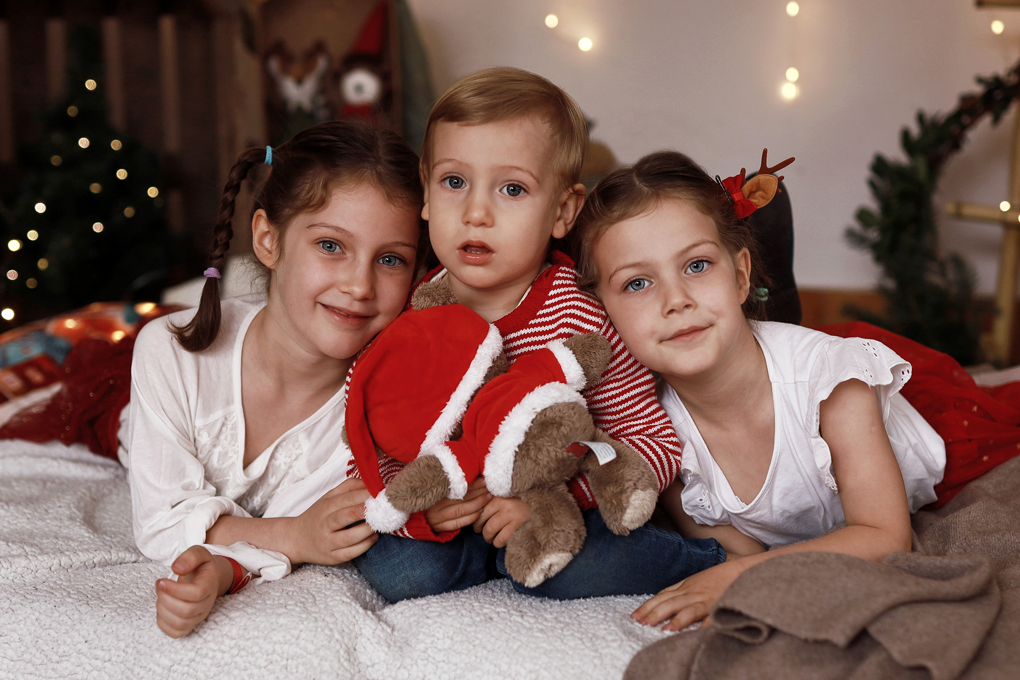 Három testvér összebújva van a karácsonyi fotózáson